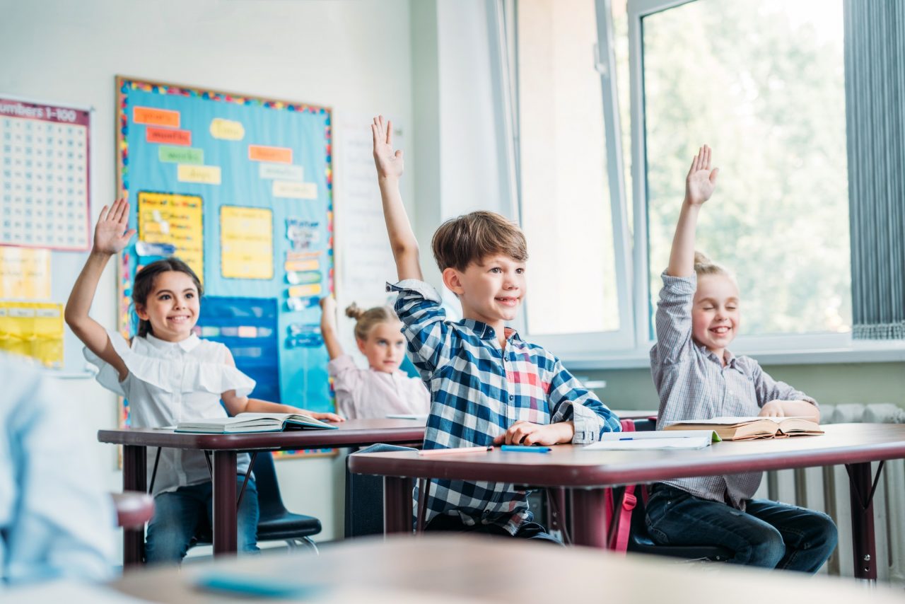 happy little kids raising hands in class